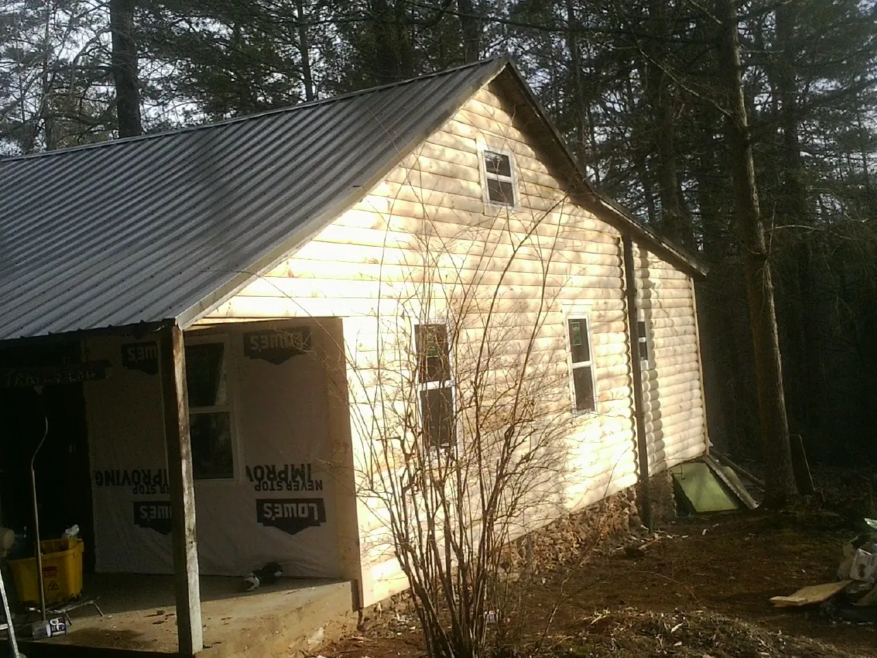Log siding gable end under a dark metal roof edge in Conrad