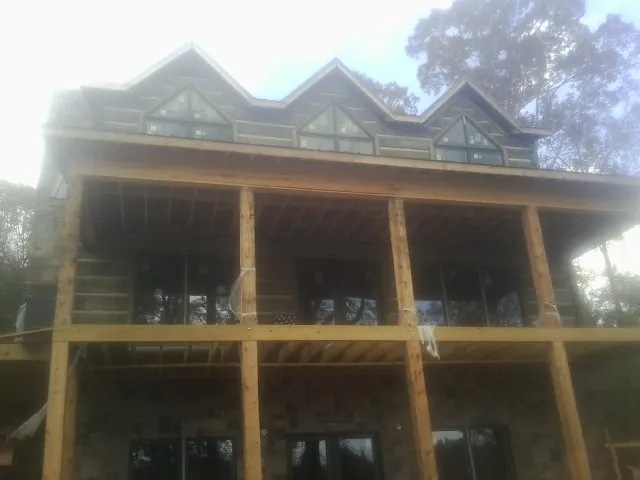 Dormers and porch framing on a large log home under construction — Roof Coating work by our crew in Conrad