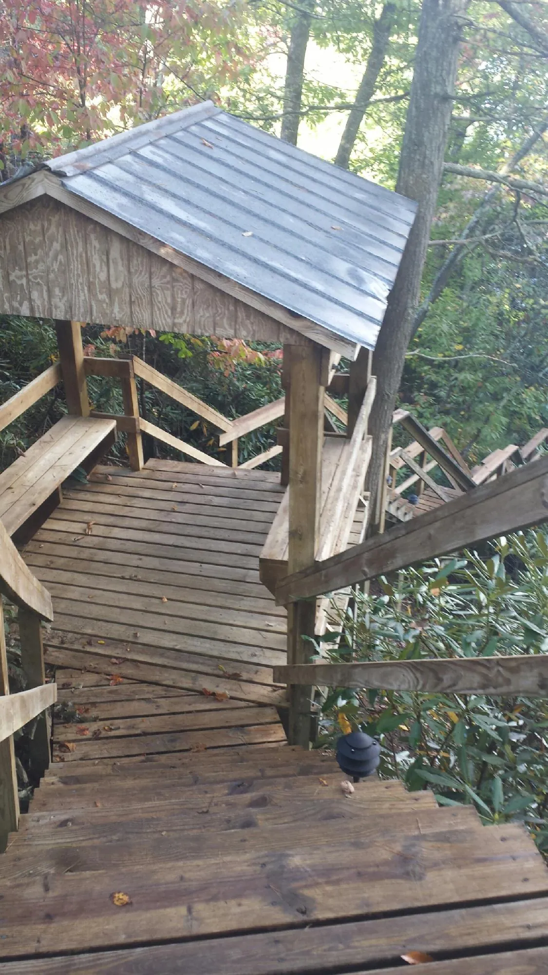 Metal roofed shelter over wooden steps on a wooded walkway — Skylight Repair & Installation work by our crew in Conrad