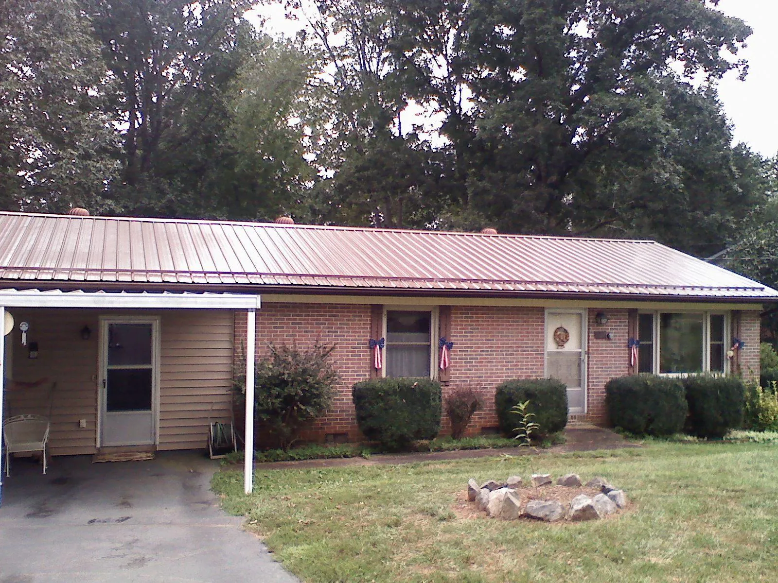 Bronze metal roof and carport on a brick ranch home — Roof Repair work by our crew in Conrad